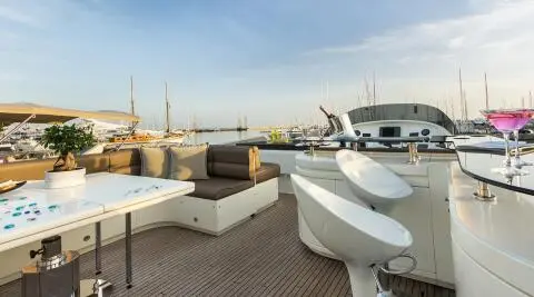 Sunlit marina deck of Amoraki yacht with seating and calm water
