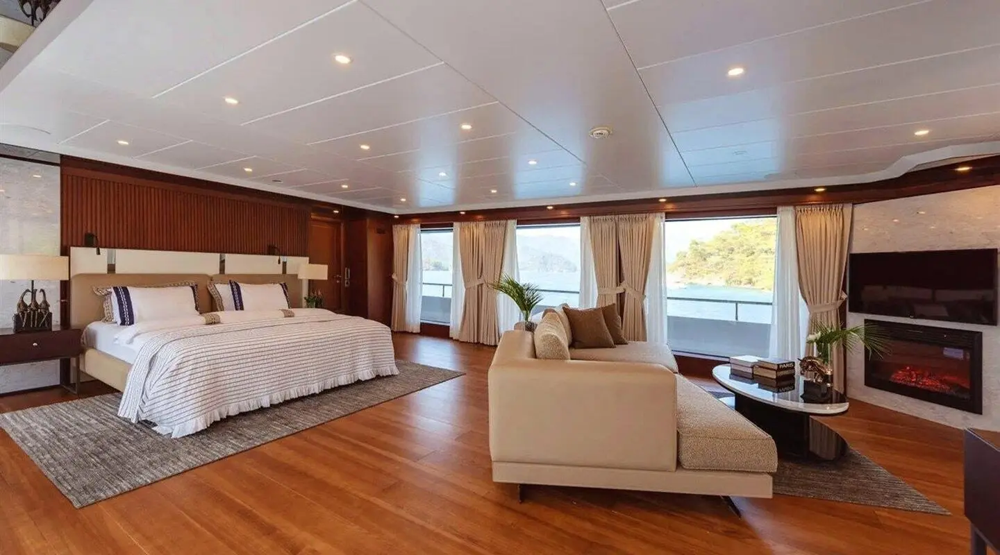 Interior of Ocean Breeze yacht showing a wood floor, bed, seating area, and large window