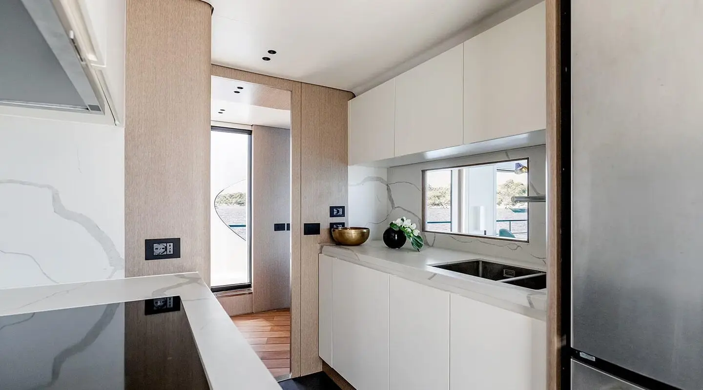 Viva II luxury yacht galley with white cabinets and marble countertops, ocean view window