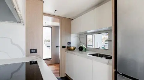 Viva II luxury yacht galley with white cabinets and marble countertops, ocean view window