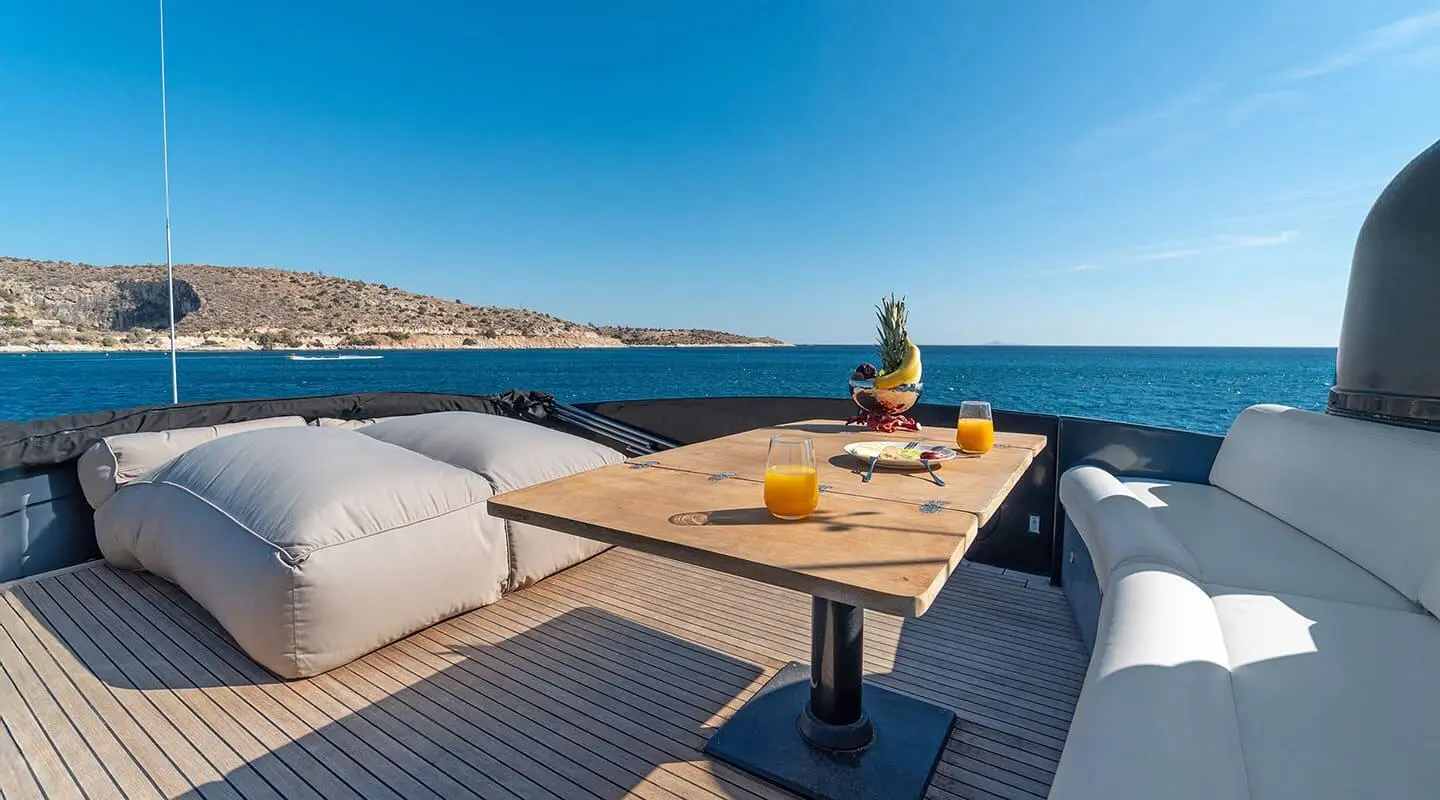 Luxurious yacht bow deck with seating, table, and sea view at dusk.