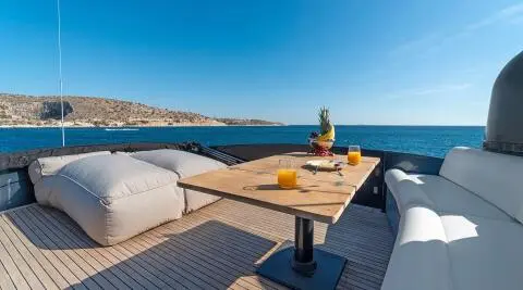 Luxurious yacht bow deck with seating, table, and sea view at dusk.