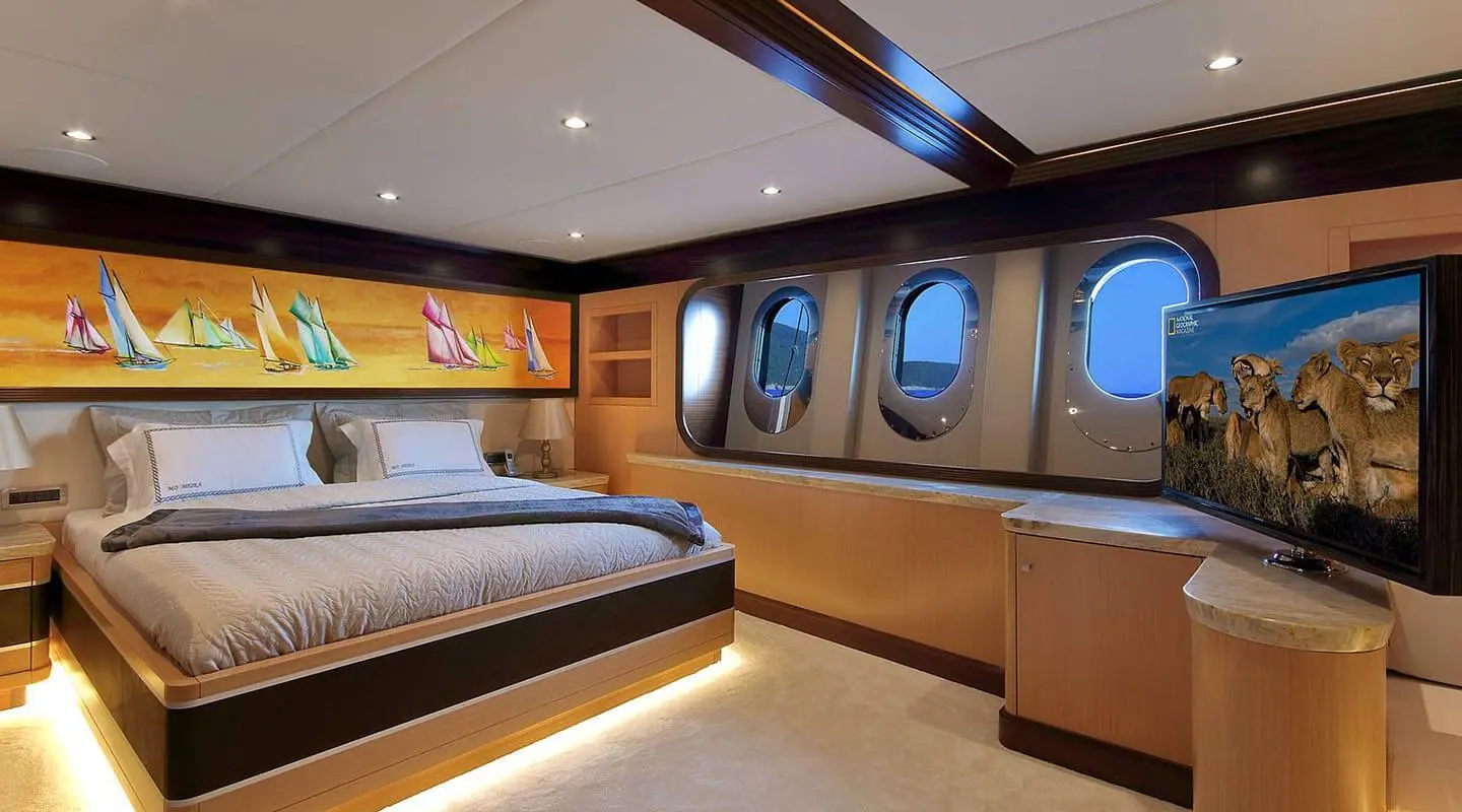 Meira luxury yacht bedroom with large bed, windows, wood paneling, and ambient lighting