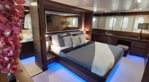 Miraval yacht bedroom with bed, blue lighting, dark wood cabinets