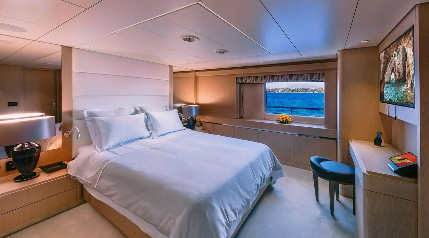 Xana yacht bedroom with a large bed, wooden cabinetry, and a window view