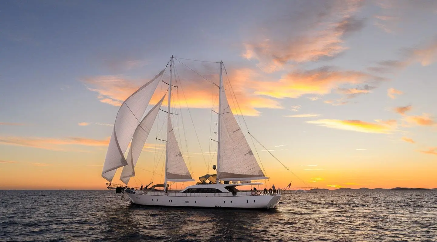 Alessandro I sailing at sunset with full white sails on calm sea
