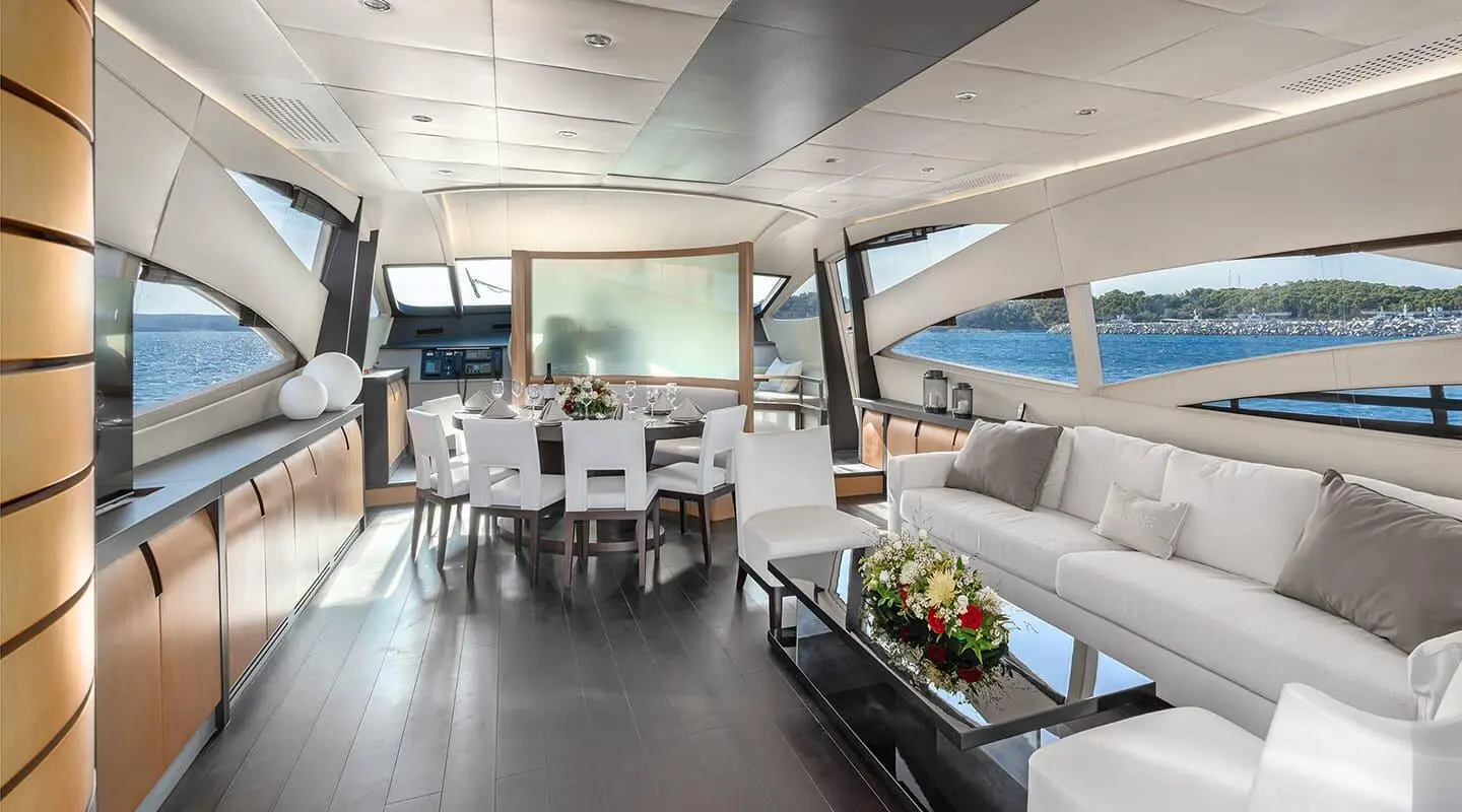 Spacious yacht salon with dining table, seating, and panoramic window view