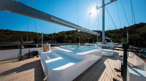 Nocturno yacht deck with white seating and sun-drenched view, sunset horizon