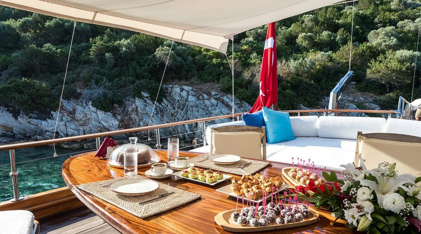 Grace 1 yacht deck with wooden table set for dining, appetizers and drinks