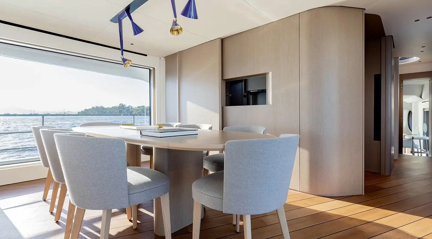 Viva II yacht saloon interior with light wood, seating, dining table and windows