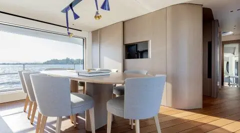 Viva II yacht saloon interior with light wood, seating, dining table and windows