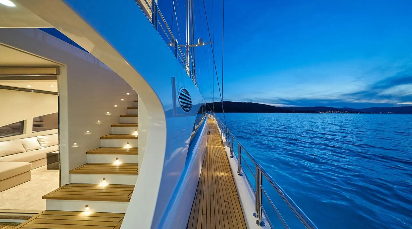 Sunset-lit yacht deck with polished railings and calm sea surrounding Acapella