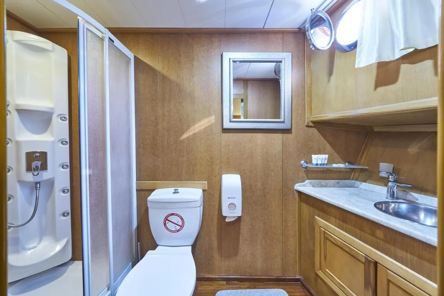 Morning Star yacht interior with wooden cabinets, sink, mirror, toilet, and beige tiled walls