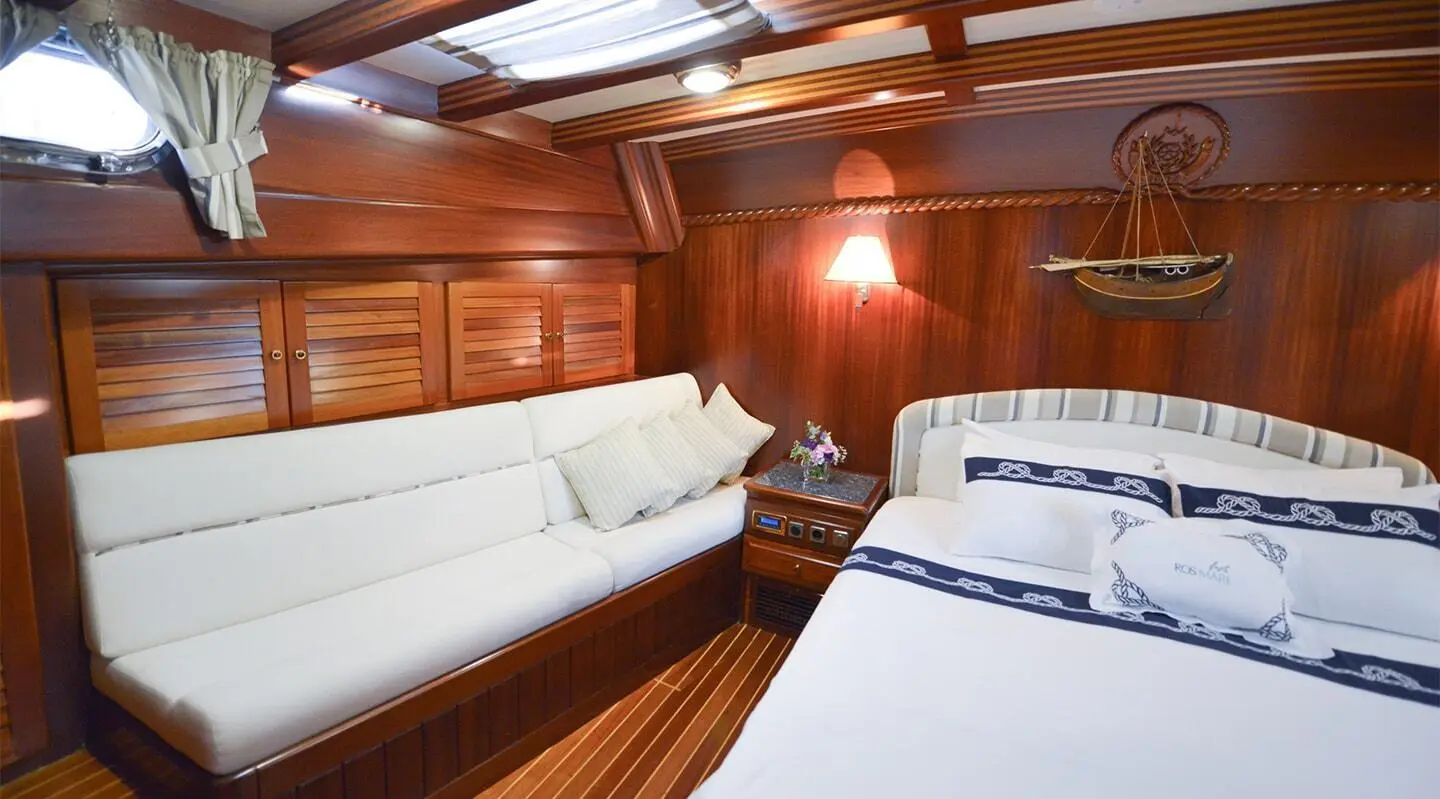 Luxurious yacht Ros Mare interior with wood paneling, white seating and cabin beds