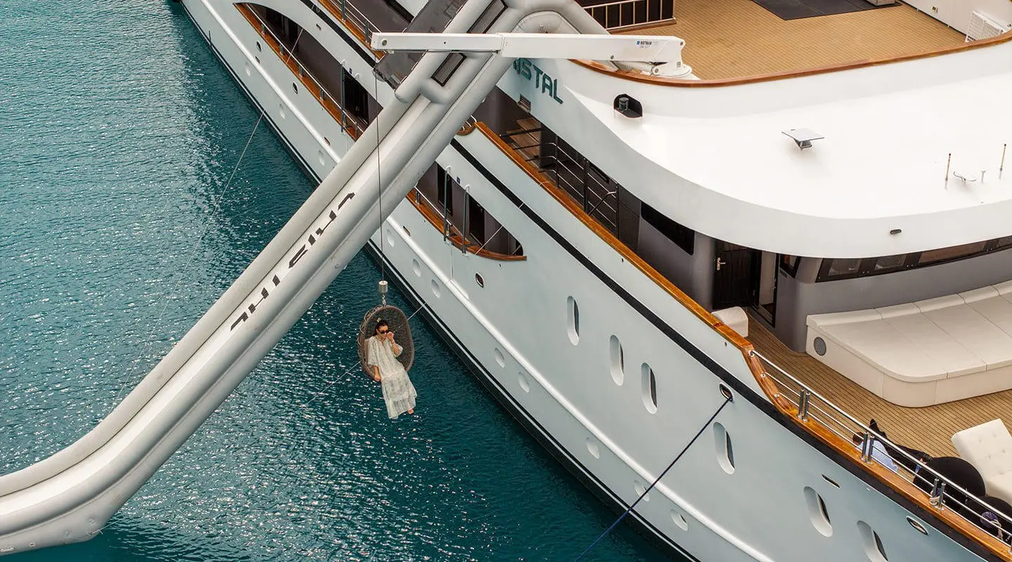 Yacht Cristal seen from the water with a person climbing aboard near the hull