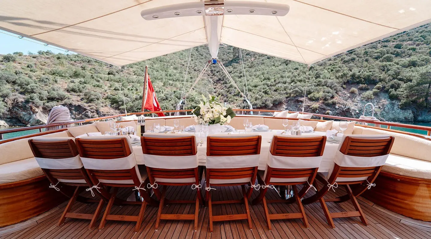 Lycian Queen yacht deck with red-cushioned seating and shade canopy at sunset