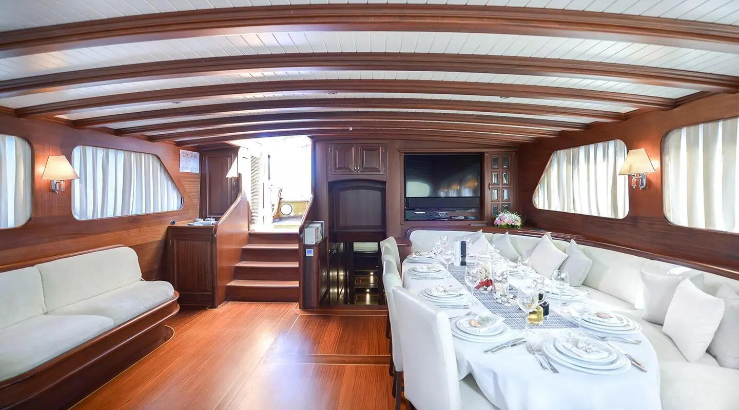 Luxurious yacht interior with a long white-dressed dining table and wood paneling