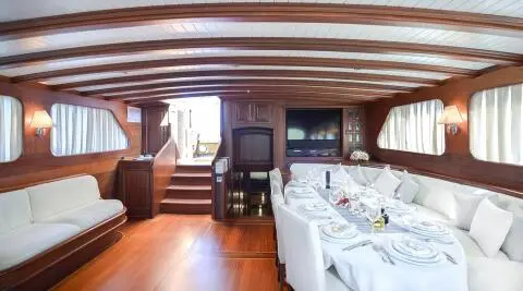 Luxurious yacht interior with a long white-dressed dining table and wood paneling