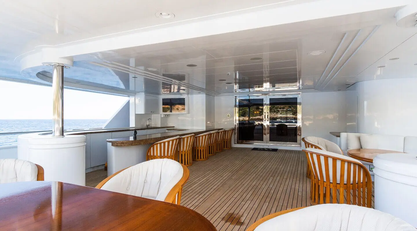 Deck scene of Apogee luxury yacht with seating, table, and ocean view