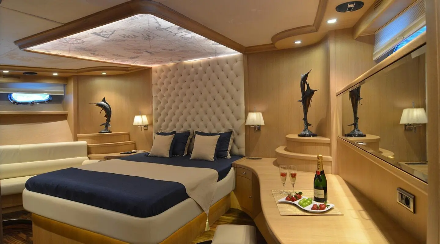 Interior luxury cabin on Blue Heaven yacht with bed, seating, and warm lighting