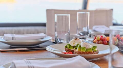 Christal Mio yacht dining on deck with avocado toast and fresh fruit