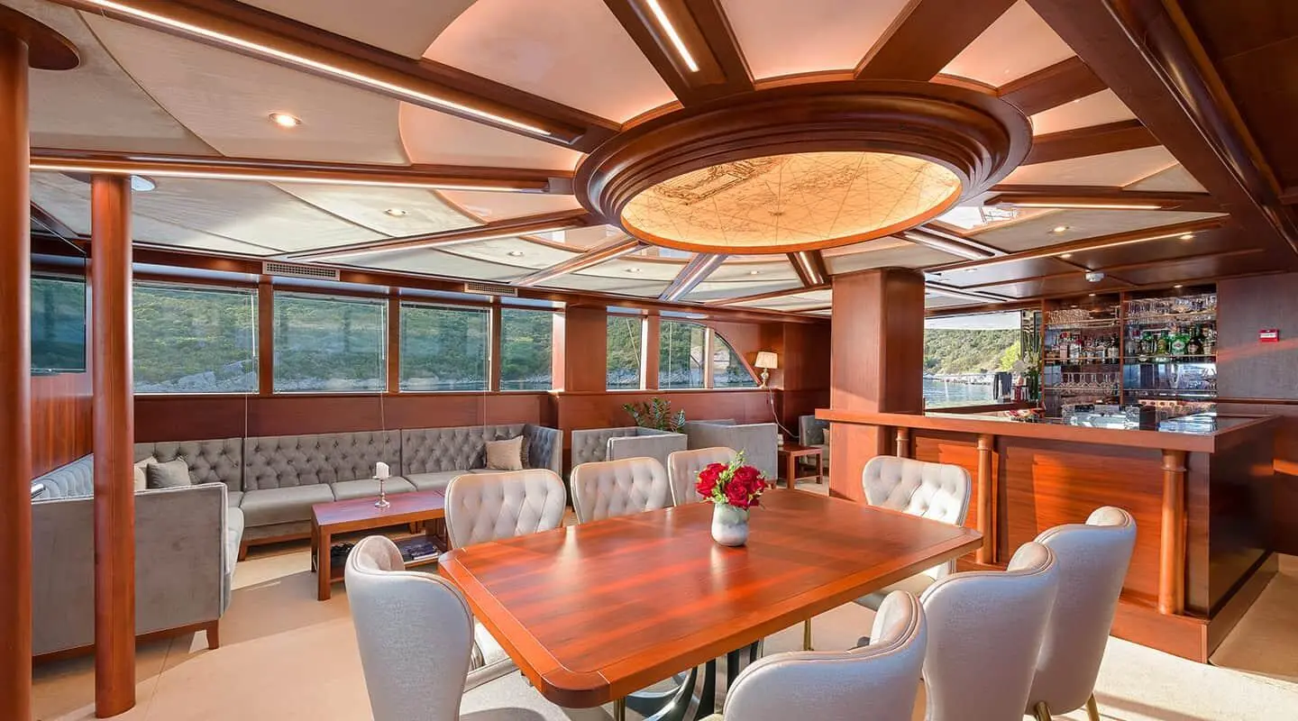 Interior salon of Lady Gita yacht with wooden table and chairs, warm lighting