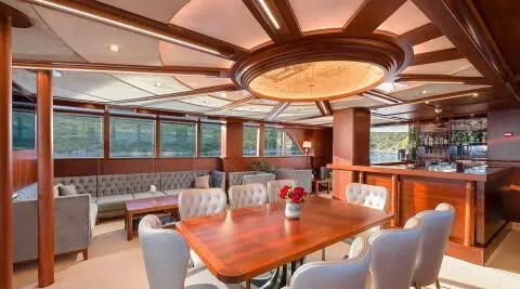 Interior salon of Lady Gita yacht with wooden table and chairs, warm lighting