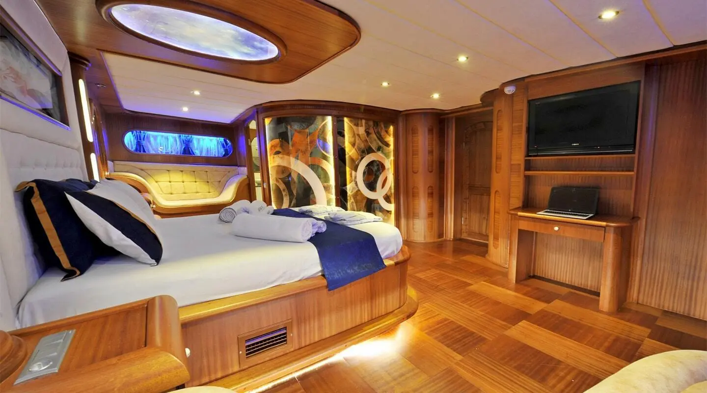 Gulet Berrak Su master cabin interior with wooden panels and bed