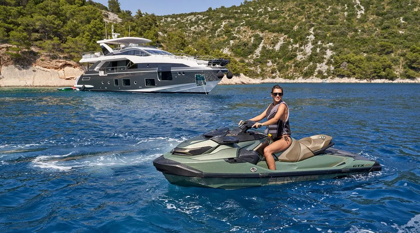 Yacht Aluminia Too anchored offshore with a person riding a small motorboat nearby
