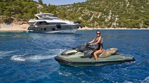 Yacht Aluminia Too anchored offshore with a person riding a small motorboat nearby