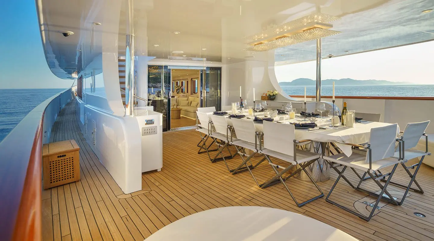 Maia yacht dining on deck with panoramic sea view and open-air table setting