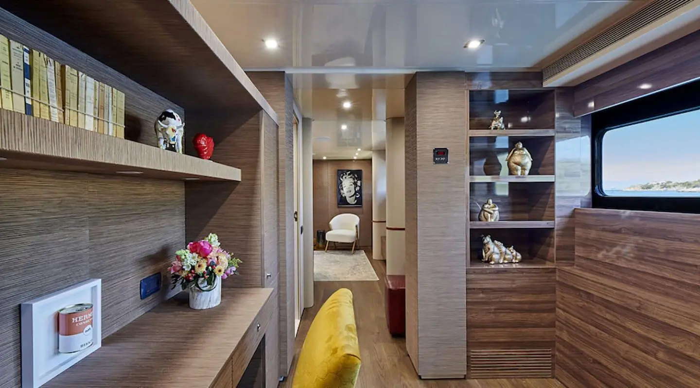 Yacht Daloli interior with plush yellow chair, wooden shelves, and decorative lighting