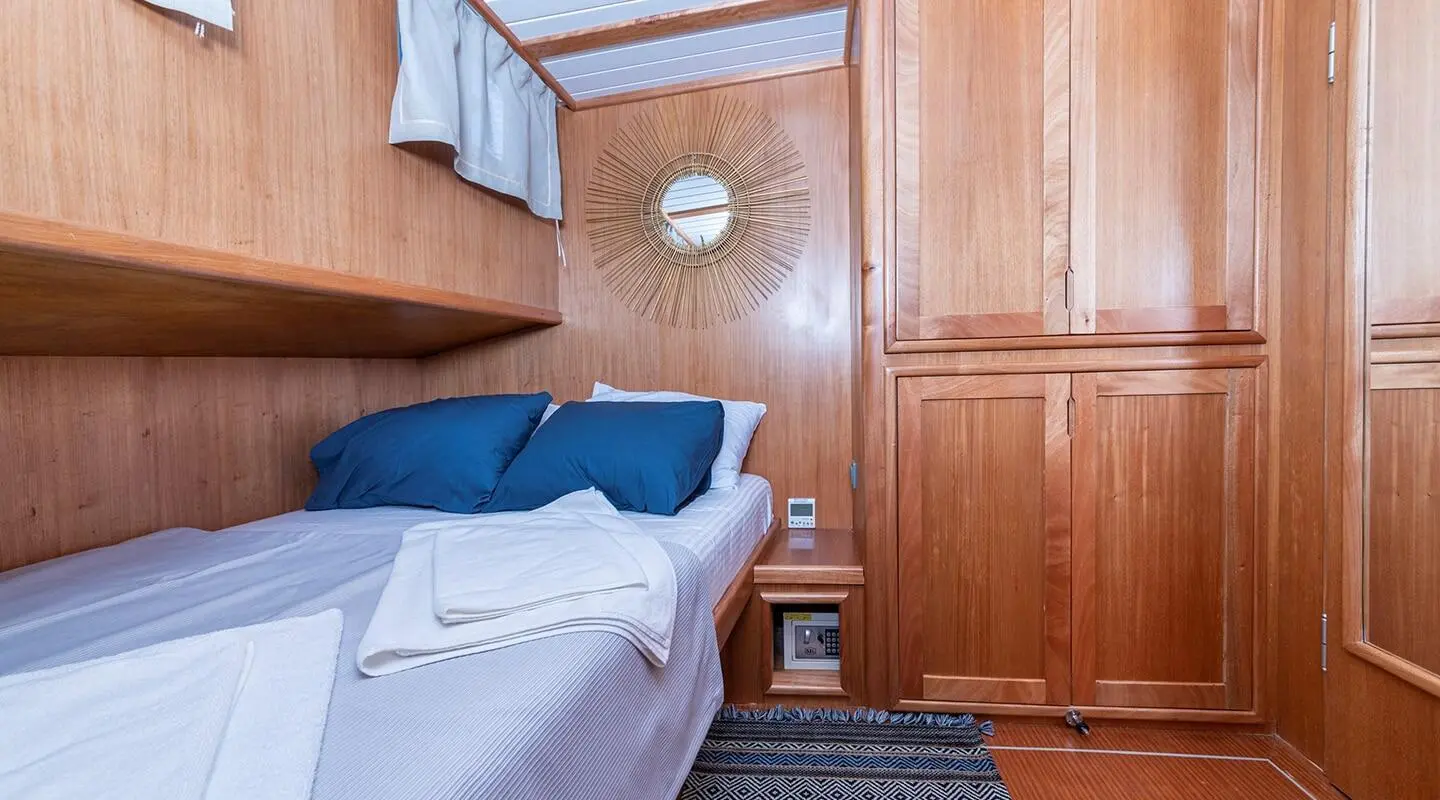 Yacht Bodrum Queen cabin interior with wood walls, bed and blue cushions