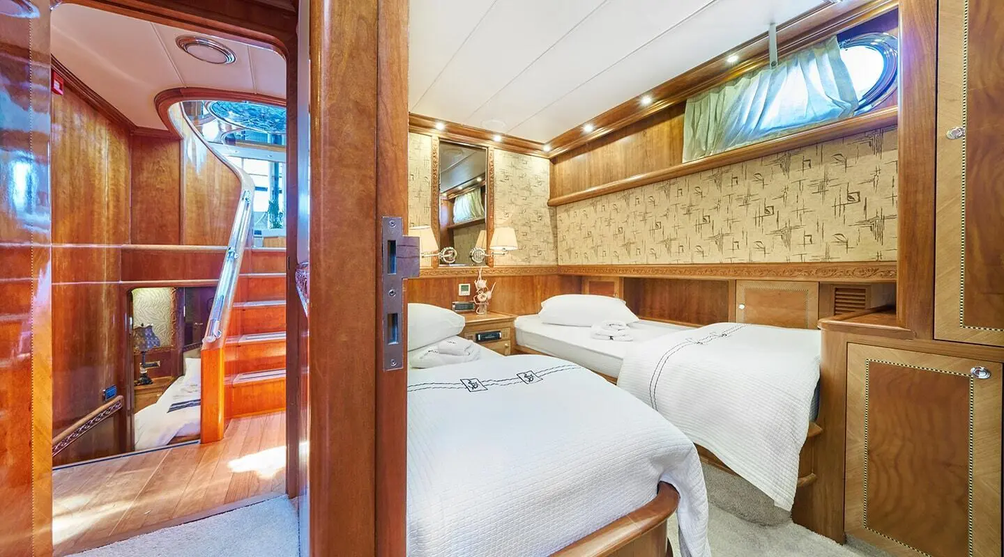 Lotus yacht interior: two white beds, wood cabinets, warm lighting