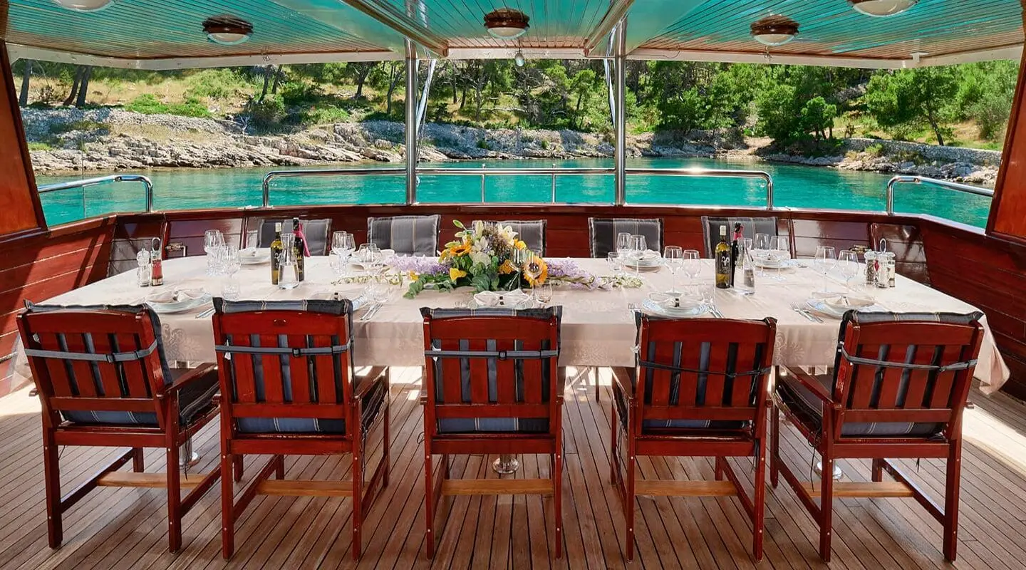 Luna yacht dining area on deck with wooden chairs and sunset views