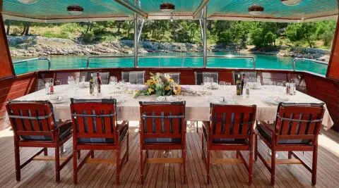 Luna yacht dining area on deck with wooden chairs and sunset views