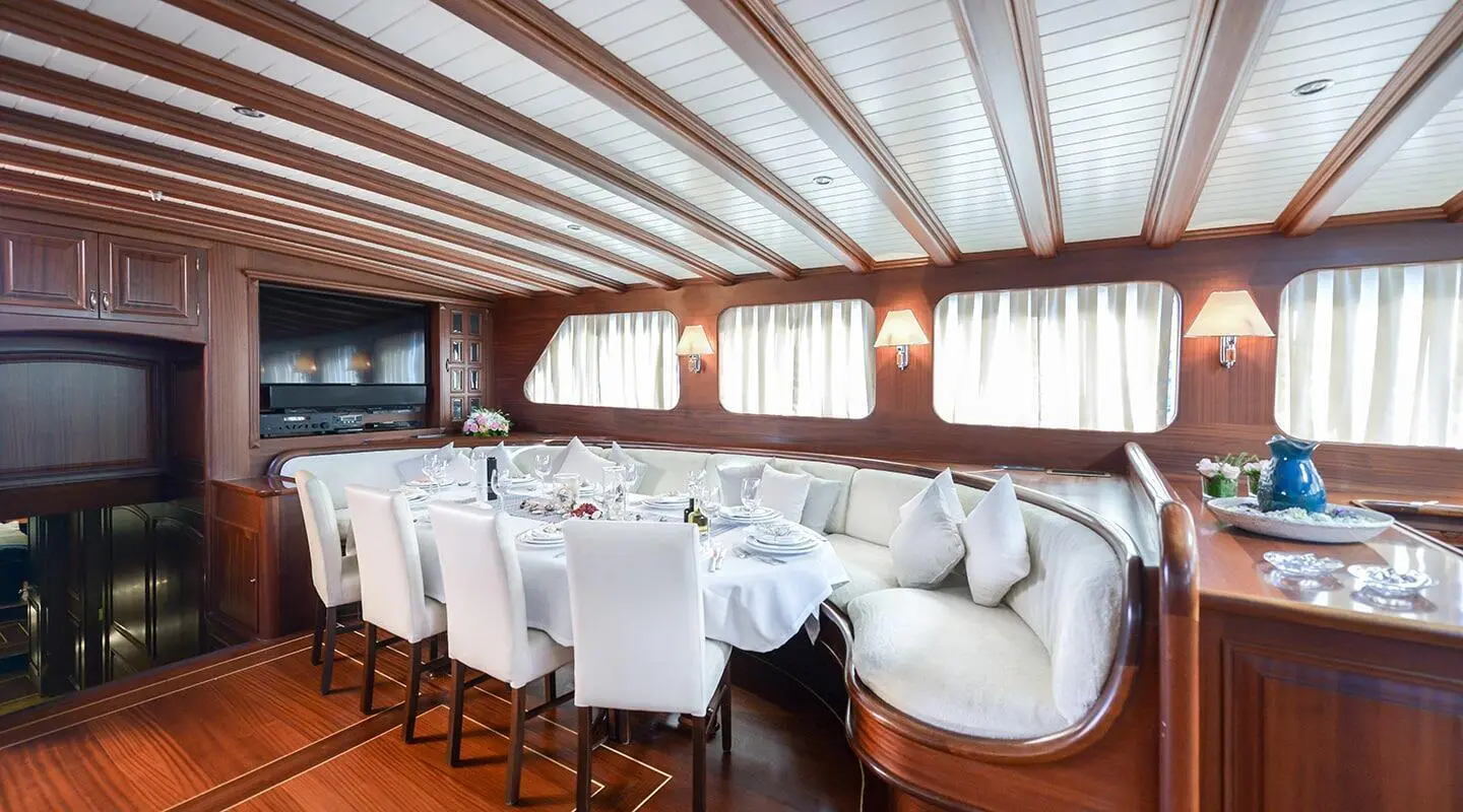Interior dining salon on Lady Christa yacht with white table settings and curved seating