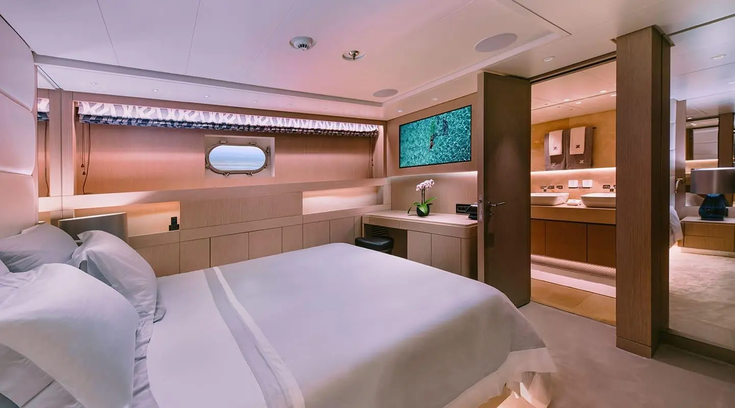 Xana yacht bedroom with large bed, wooden panels, and built-in cabinets