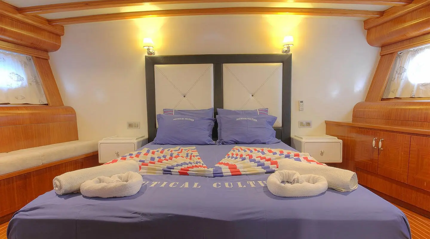 Angelo II master cabin with two single beds and teal cushions on bedheads