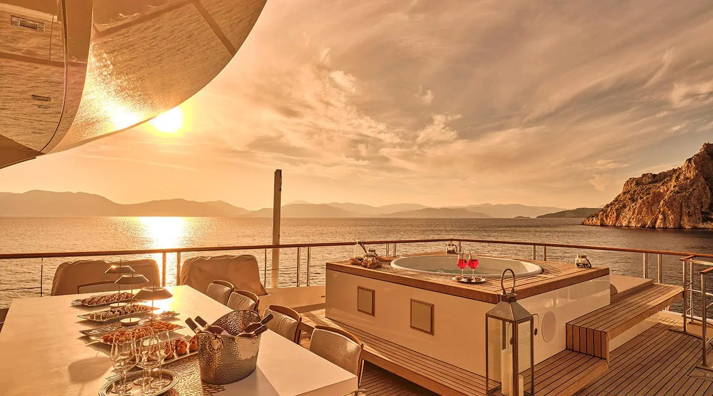 Sunset over a yacht deck with railings, ropes, and cabin visible