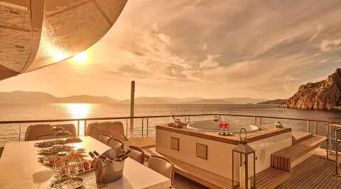 Sunset over a yacht deck with railings, ropes, and cabin visible