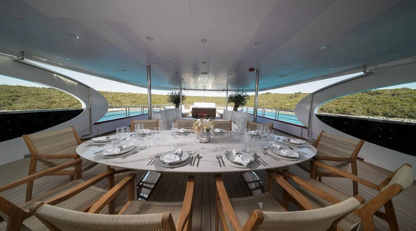 Olimp motor yacht dining table set on deck with chairs under shaded canopy