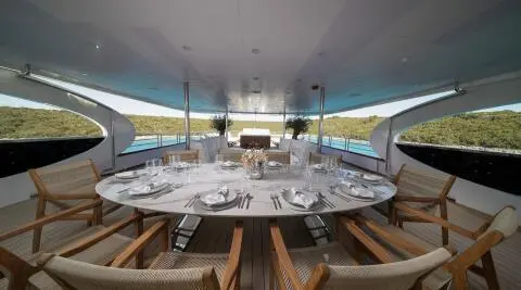 Olimp motor yacht dining table set on deck with chairs under shaded canopy