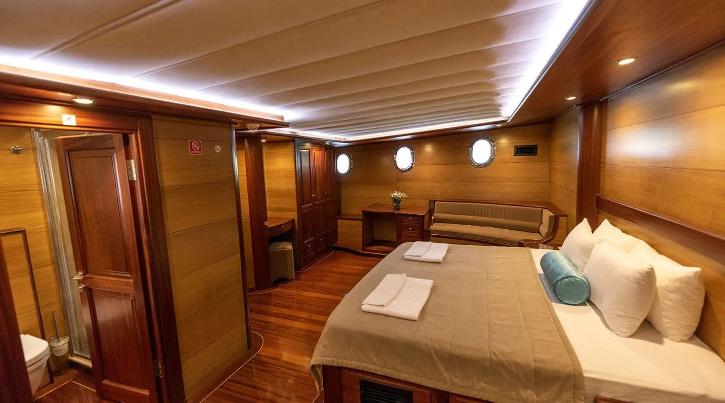 Kayhan 4 luxury yacht interior: wood-paneled cabin with a large bed and seating area