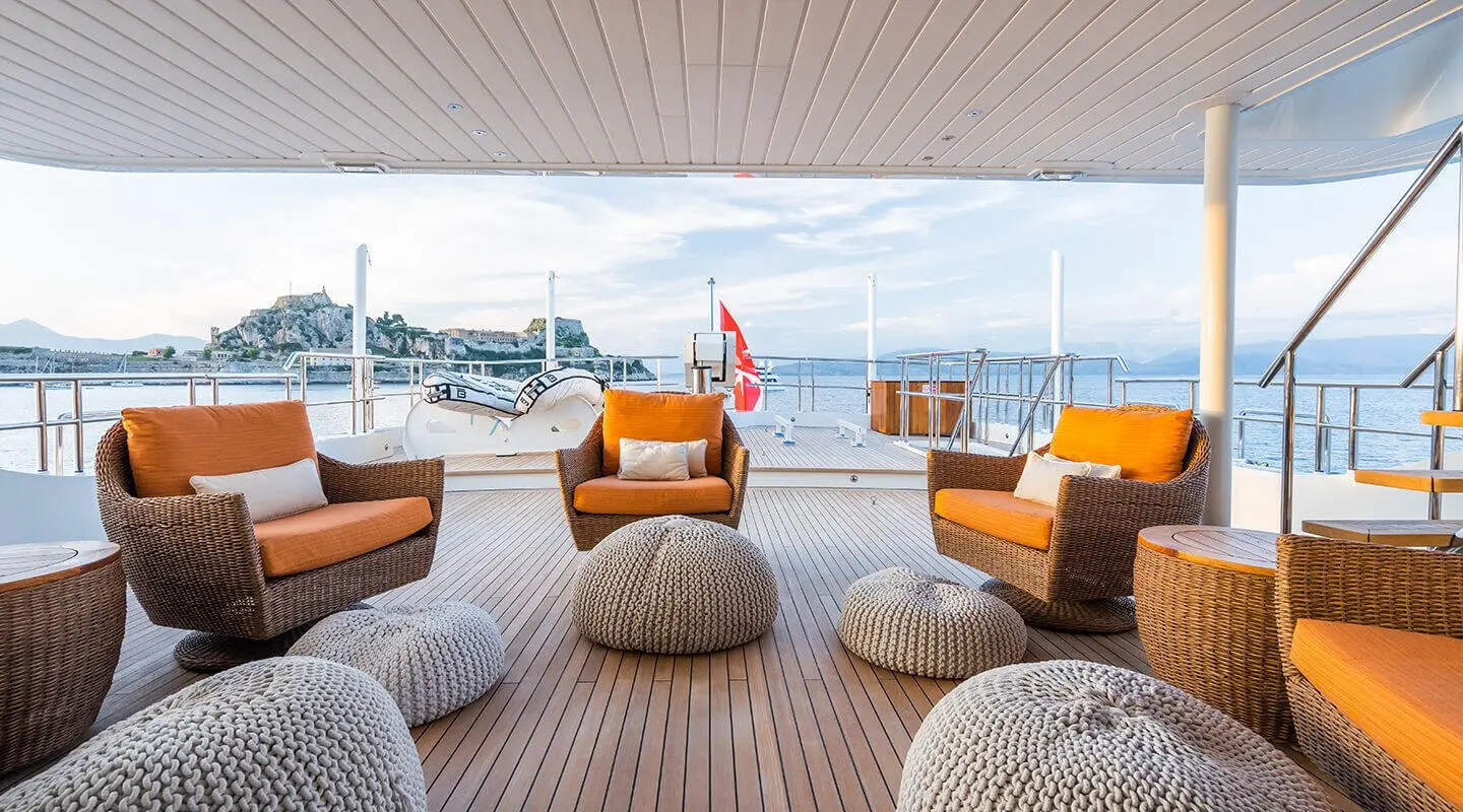 Serenity yacht deck seating area with cushioned orange chairs under a shaded awning