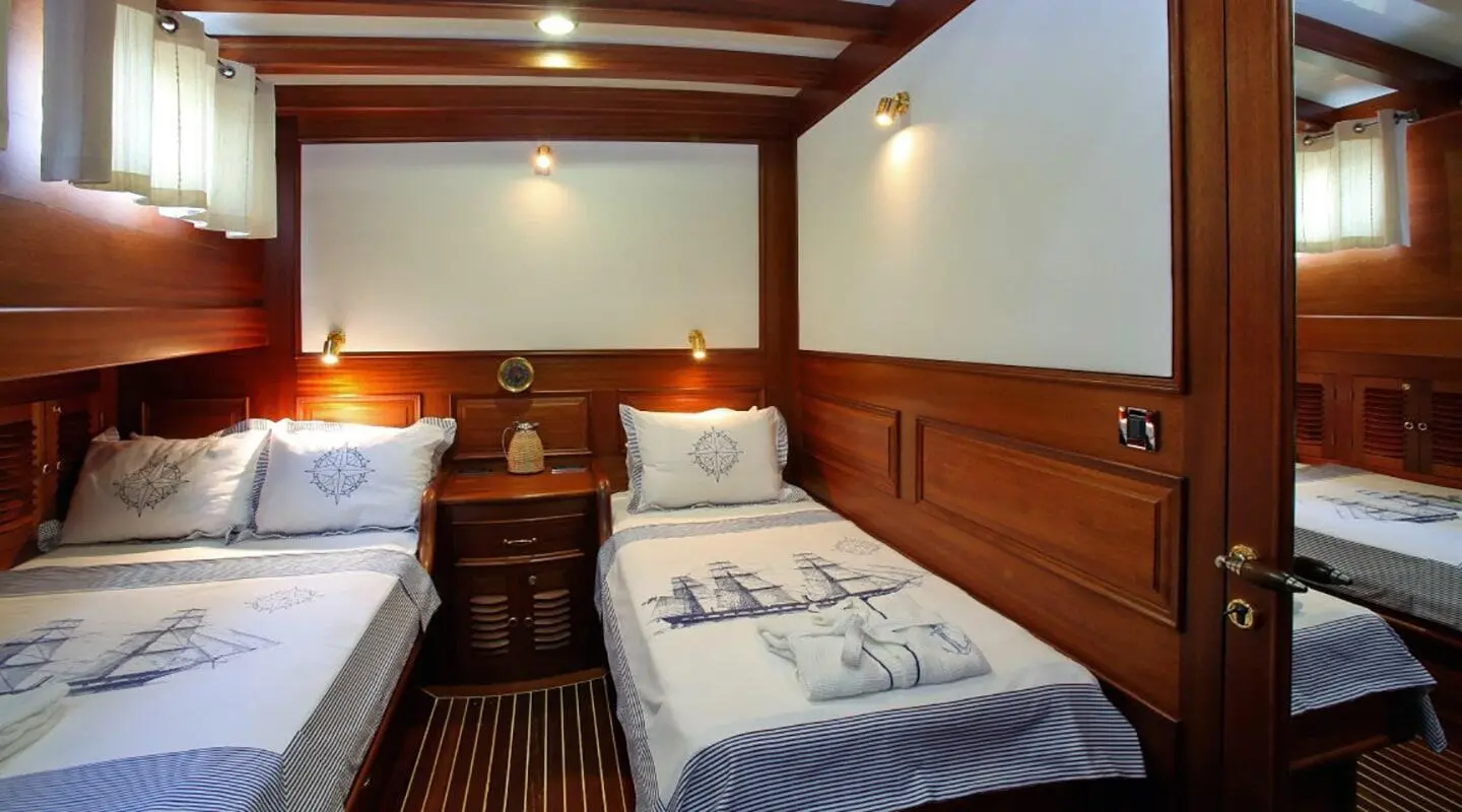Kaya Guneri 4 yacht interior: twin beds, wood-paneled walls, bedside lamps