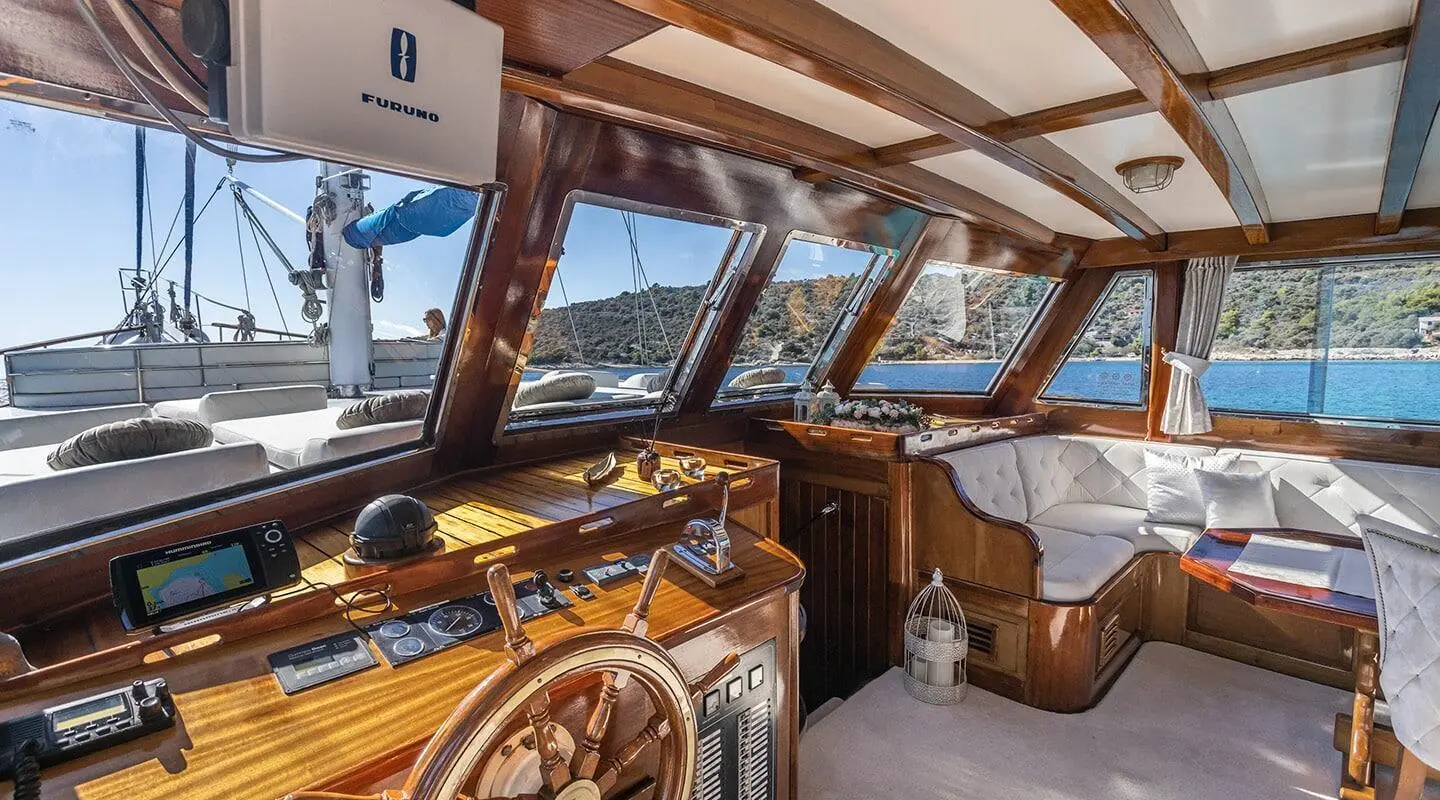 Interior of a luxury yacht with wooden helm and windows showing sunset