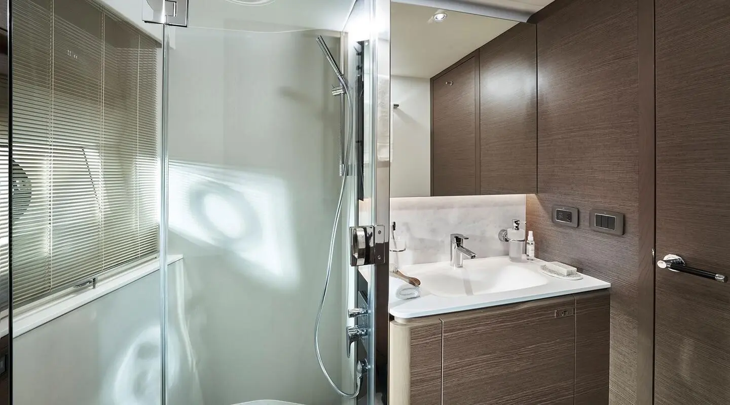 Bathroom on yacht Elizabeth with glass shower door and marble sink area