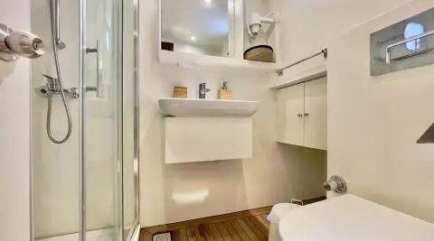Interior shot of a compact yacht head with shelves, mirror, and cabinet doors