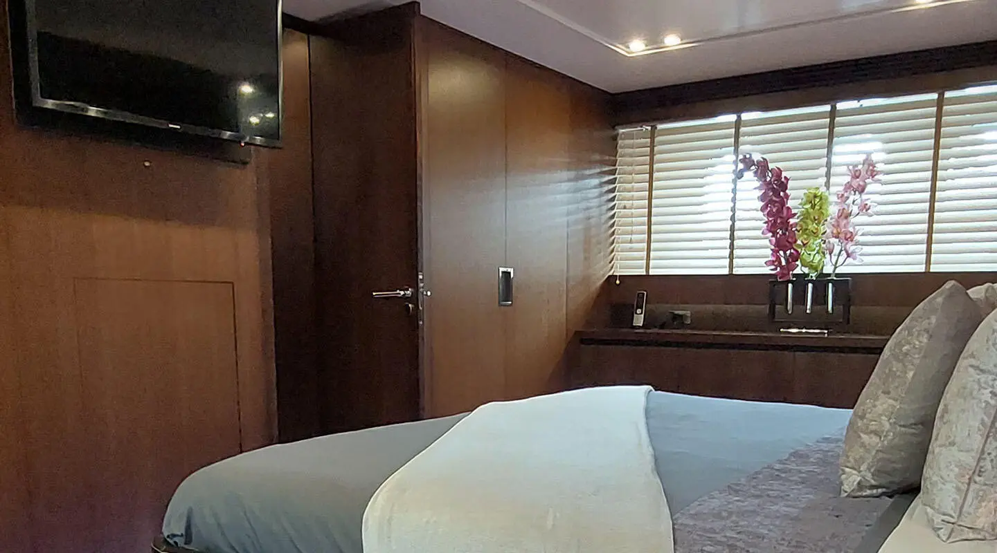 Miraval yacht deck with white bed, wood paneling, cabin windows, and blue bedding